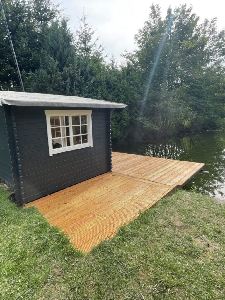 Direkt am Wasser ist die graue Hütte von einem Seg umgeben, der über das Wasser ragt. Der perfekte Wetterschutz direkt am Wasser.